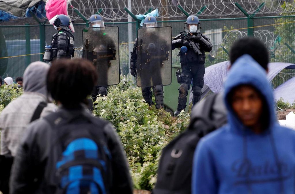 Migrant camp evacuated on second attempt after fierce clashes – video